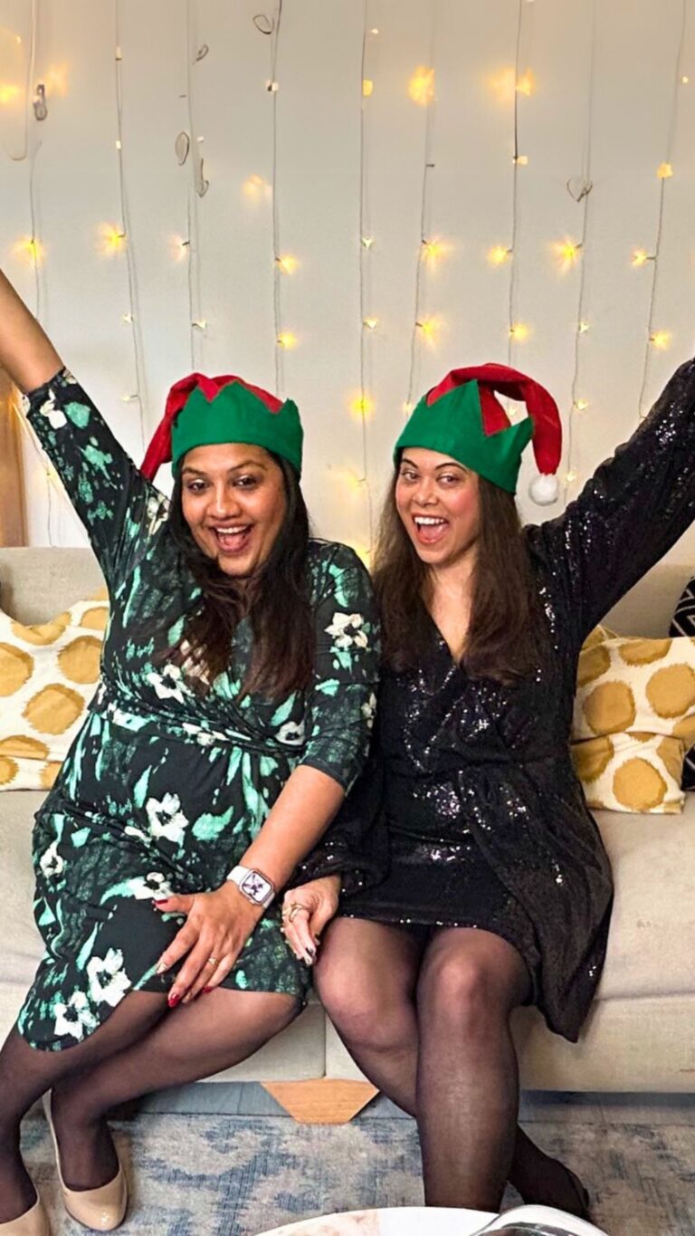Podcast hosts Pooja and Nikita looking all cheery at the camera and celebrating christmas.